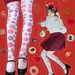 Op de afbeelding: Witte panty's met een patroon van roze en paarse knopen, aardbeien en sterren. De panty's worden gedragen met zwarte schoenen. De afbeelding toont ook een persoon met een rode baret, witte blouse en bordeauxrode rok, die een vintage telefoon vasthoudt.