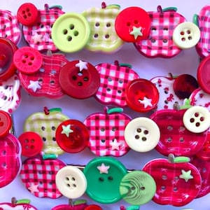 Puede incluir: Una colección de botones con forma de manzana con patrones de cuadros rojos, verdes y blancos, intercalados con botones redondos de colores sólidos en rojo, verde lima y crema. Pequeños adornos en forma de estrella blanca decoran varios botones.