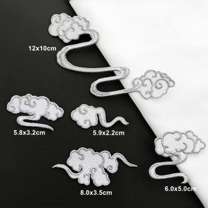 May include: Five white embroidered iron-on patches in the shape of clouds with swirling designs. The patches are different sizes, ranging from 5.8 x 3.2 cm to 12 x 10 cm.