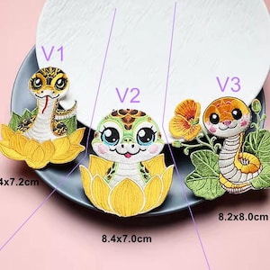 May include: Three embroidered iron-on patches featuring cartoon snakes with different designs. The patches are approximately 8.4x7.2 cm, 8.4x7.0 cm, and 8.2x8.0 cm.