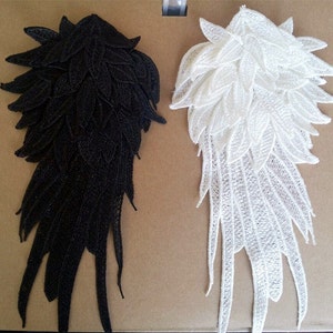 May include: Two pairs of black and white lace wings. The wings are made of delicate, intricate lace and have a feathered design. They are perfect for adding a touch of elegance to any project.