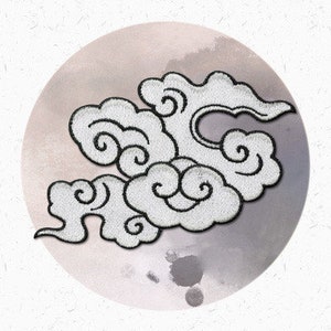 以下が含まれることがあります： 黒色のアウトラインで白く刺繍された雲のデザイン。雲のデザインは渦巻く形にスタイリッシュにデザインされており、日本の伝統的な芸術を彷彿とさせます。
