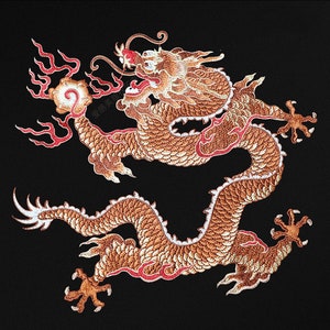 May include: A gold embroidered dragon with red accents on a black background. The dragon is curled up with its head facing the right side of the image. The dragon's scales are detailed and the embroidery is intricate.