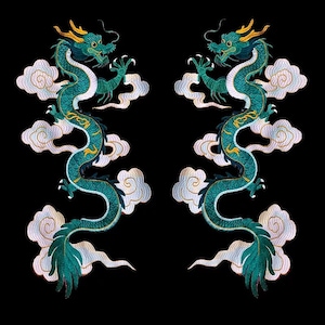 May include: Two symmetrical embroidered patches featuring long, serpentine dragons in shades of teal and green with gold accents. Each dragon is depicted with claws extended, surrounded by stylised white and light purple clouds on a black background.