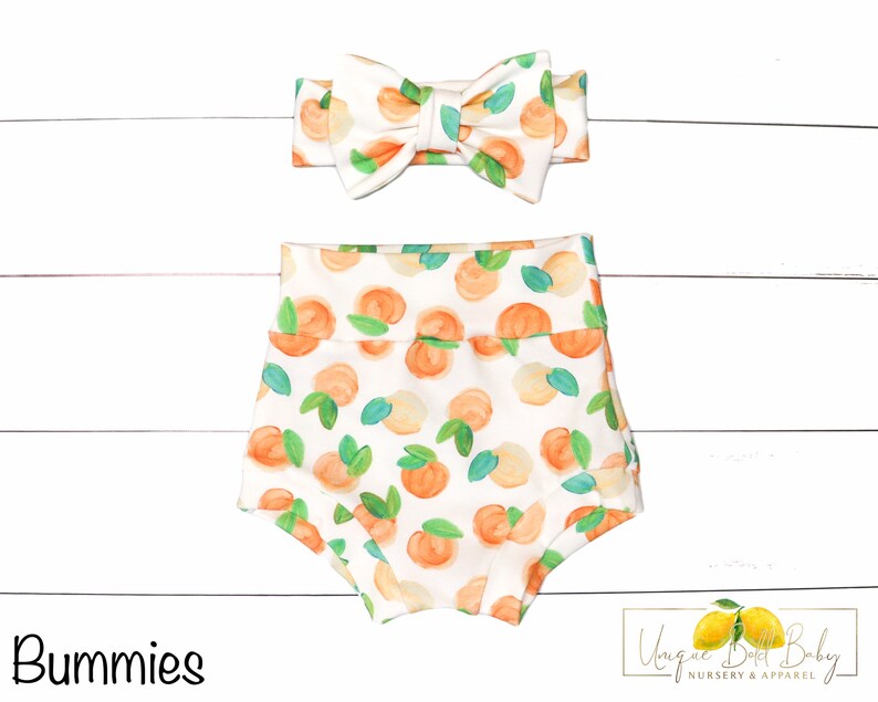 May include: White baby bloomers with a peach print and a matching peach print headband. The headband has a bow in the center. The text "Bummies" is in the lower left corner of the image. The text "Unique Little Baby Nursery & Apparel" is in the lower right corner of the image.