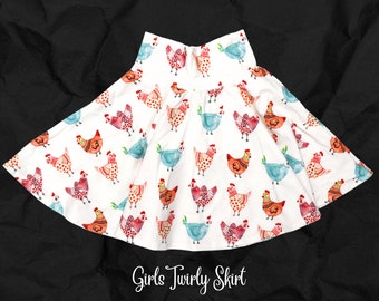 May include: White twirly skirt with a colorful chicken print. The skirt has a wide elastic waistband and is available in sizes 2T-12. "Girls Twirly Skirt" is written in black text at the bottom of the image.