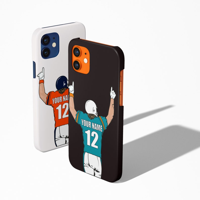 May include: Two phone cases featuring a black and white illustration of a football player raising their arms in celebration. The player is wearing a teal and white jersey with the number 12 on the back. The text "YOUR NAME" is above the number. The phone case on the left is white with a black and orange illustration of a football player raising their arms in celebration. The player is wearing an orange jersey with the number 12 on the back. The text "YOUR NAME" is above the number.