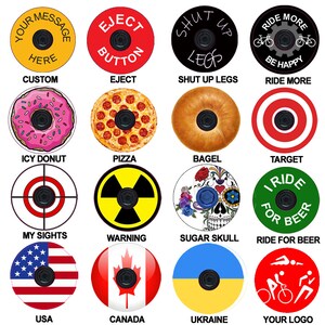 May include: A set of 16 colorful bike stem caps with various designs, including a donut, pizza, bagel, target, skull, warning sign, American flag, Canadian flag, Ukrainian flag, and a logo. The caps are round and have a hole in the center for the stem.