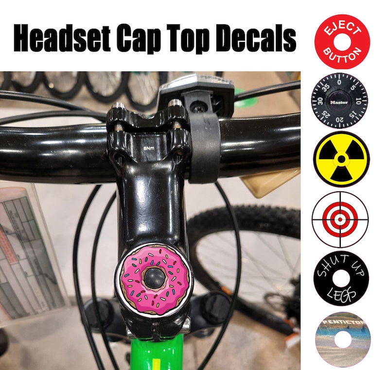 May include: A close-up of a bicycle headset cap with a pink donut sticker. The sticker has pink frosting and colorful sprinkles. The bicycle headset cap is black and has a 5mm bolt. The image also shows a variety of other stickers, including a red target, a yellow and black radiation symbol, a black and white sticker with the text "Shut Up Legs", and a red sticker with the text "Eject Button".