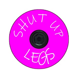 May include: A bright pink bicycle stem cap with white text that reads "SHUT UP LEGS".