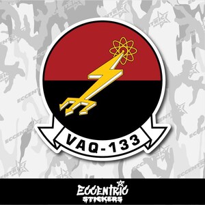 May include: A sticker featuring a circular emblem with a red and black background. A yellow lightning bolt with a trident base and atom symbol is in the center. The text "VAQ-133" is on a white banner. The sticker has the text "ECCENTRIC STICKERS".