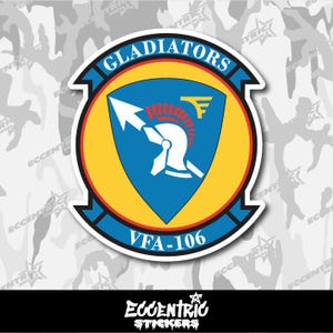 May include: A circular sticker featuring the text "GLADIATORS" in white on a blue banner. The center design includes a blue shield with a white arrow, a helmet, and the text "VFA-106". The sticker has a yellow and red color scheme.