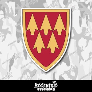 May include: A sticker featuring a shield design with a red background and six gold arrowheads. The shield has a gold border and a white outline. The sticker has the text "Eccentric Stickers" in a stylized font at the bottom.