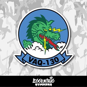 May include: A sticker featuring a green dragon with a red tongue and yellow lightning bolts against a blue background. The dragon is surrounded by white clouds and a blue banner with the text "VAQ-130". The sticker has a white border.