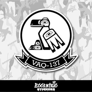 May include: A white sticker featuring a black and white stylized design of a bird within a circle. The text "VAQ-137" is displayed on a black banner below the circle. The sticker has the text "Eccentric Stickers" at the bottom.
