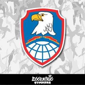 May include: A shield-shaped sticker featuring a white eagle head with a yellow beak on a blue background. The shield has a red border and includes a globe and lightning bolts. The sticker has the text "Eccentric Stickers".