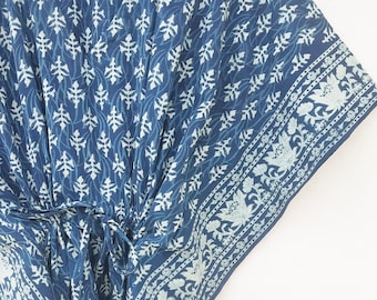 May include: A blue and white cotton kaftan with a floral print. The kaftan has a V-neck and a tie at the waist.