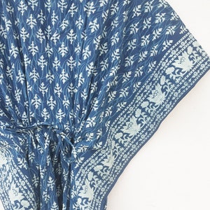 May include: A blue and white cotton kaftan with a floral print. The kaftan has a V-neck and a tie at the waist.