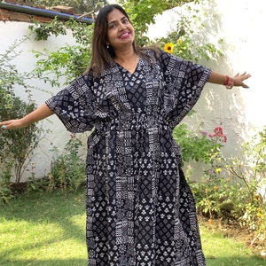 Puede incluir: Un vestido maxi estampado en blanco y negro con cuello en V y mangas 3/4. El vestido tiene una cintura con cordón y una silueta fluida.