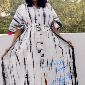 Puede incluir: Un vestido maxi de tie-dye blanco y negro con una falda larga y fluida y un lazo en la cintura. El vestido tiene una abertura lateral y se muestra en tres longitudes diferentes: hasta la rodilla, hasta la pantorrilla y hasta el tobillo. "Llevo la talla XL - talla US (10-14)" est&aacute; escrito sobre la cabeza de la modelo.