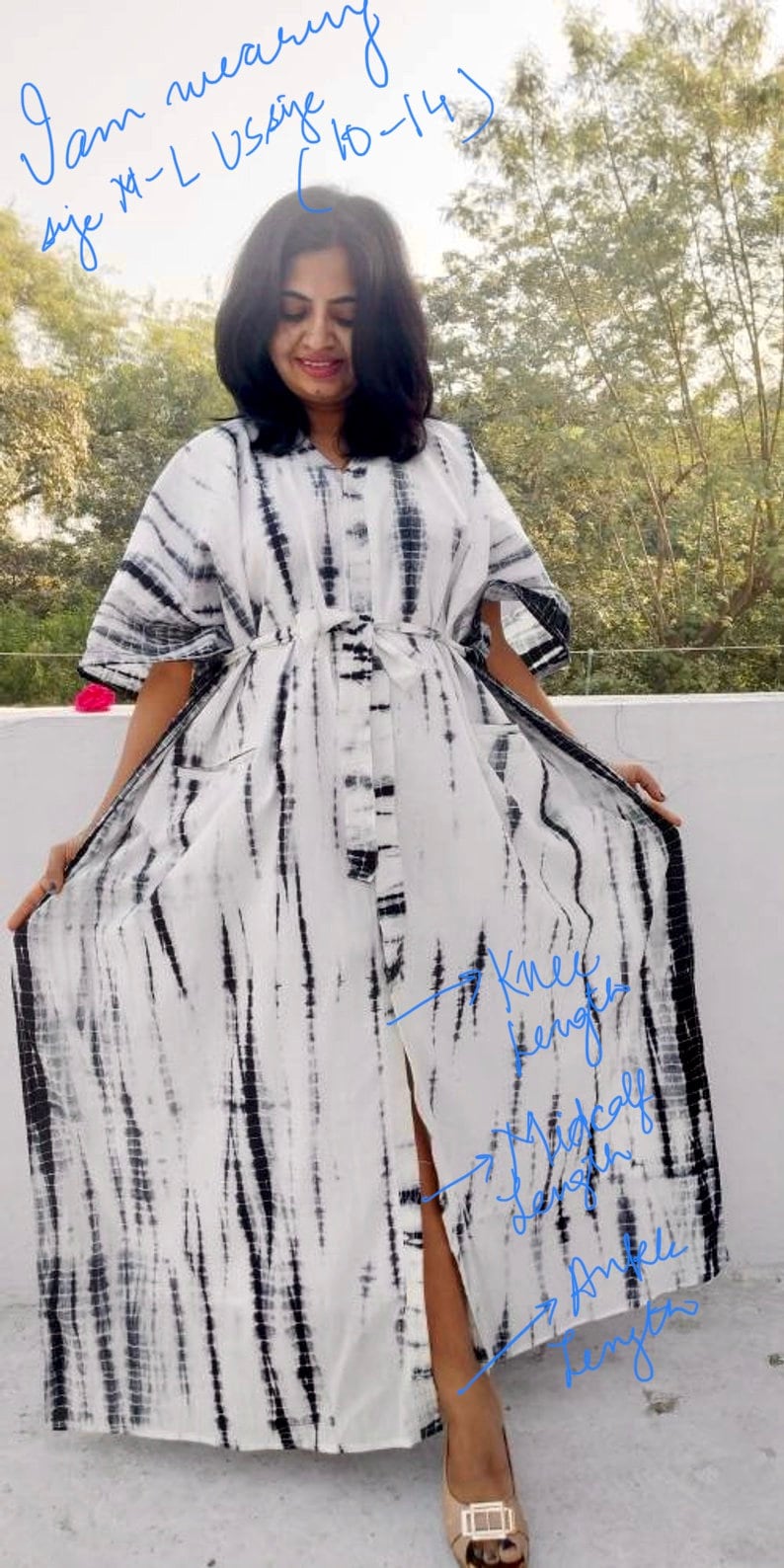 Puede incluir: Un vestido maxi de tie-dye blanco y negro con una falda larga y fluida y un lazo en la cintura. El vestido tiene una abertura lateral y se muestra en tres longitudes diferentes: hasta la rodilla, hasta la pantorrilla y hasta el tobillo. "Llevo la talla XL - talla US (10-14)" est&aacute; escrito sobre la cabeza de la modelo.