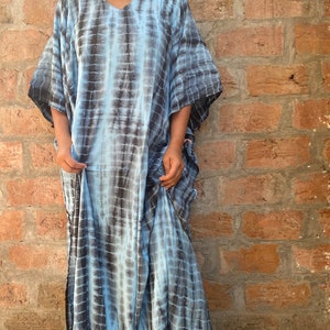 May include: A long, flowing blue and black tie-dye kaftan dress with a V-neckline and short sleeves.