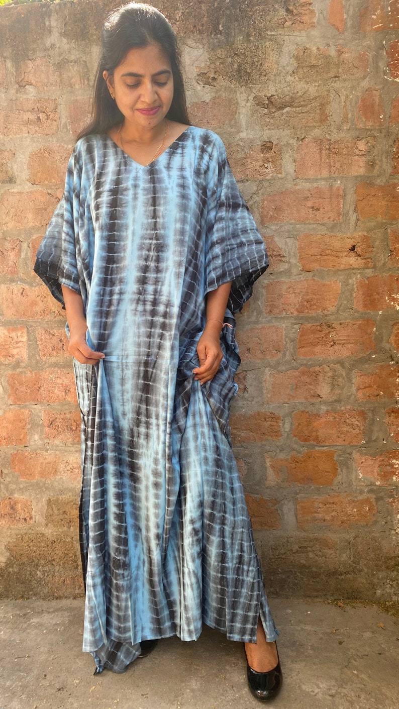 May include: A long, flowing blue and black tie-dye kaftan dress with a V-neckline and short sleeves.