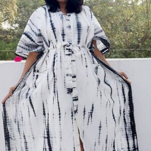 Puede incluir: Un vestido maxi blanco con un estampado tie-dye negro. El vestido tiene un frente abotonado y una falda larga y fluida.