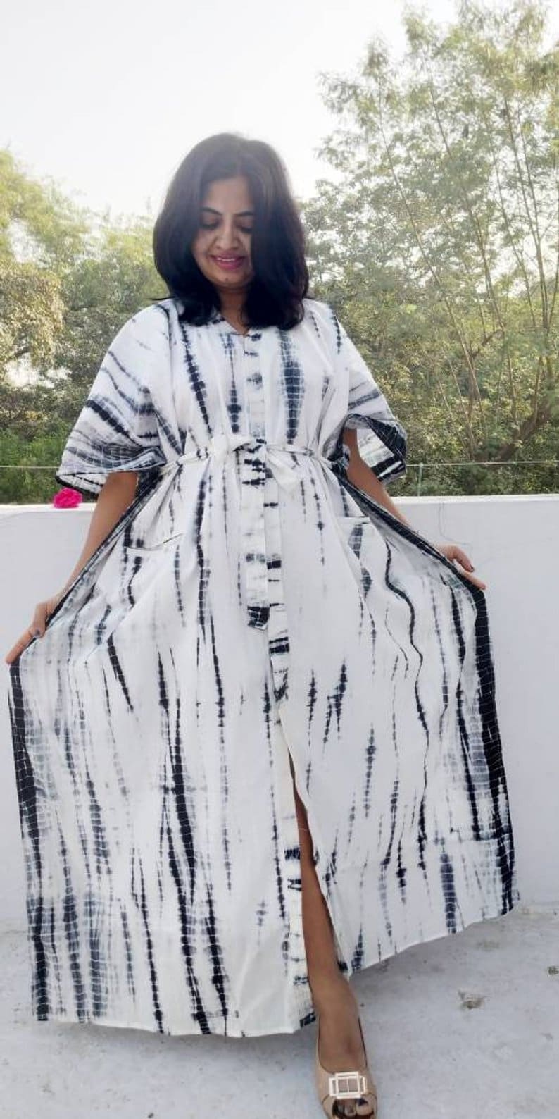 Puede incluir: Un vestido maxi blanco con un estampado tie-dye negro. El vestido tiene un frente abotonado y una falda larga y fluida.