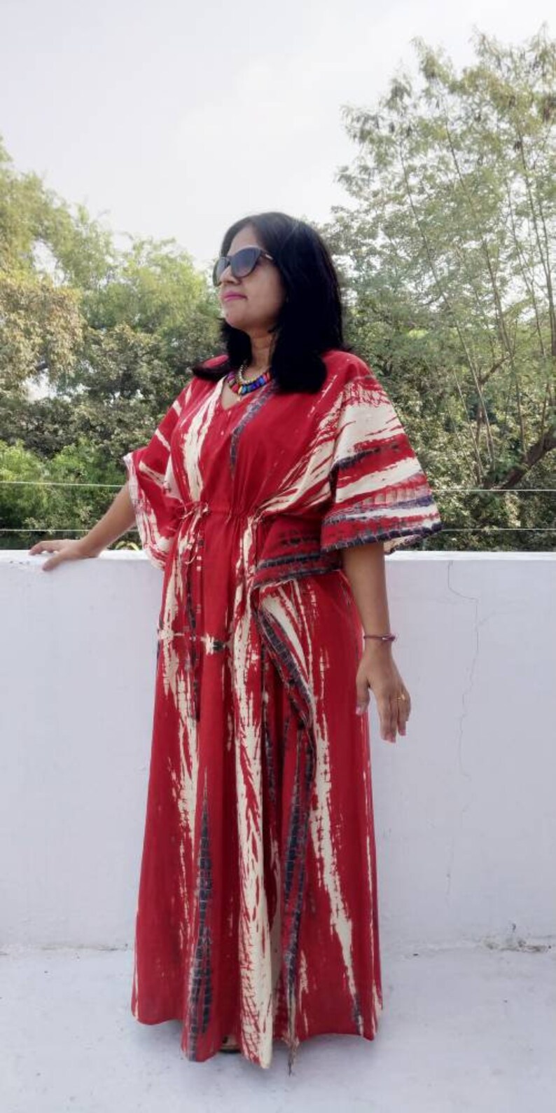 Puede incluir: Una kaftan de color rojo y blanco con estampado tie-dye y cintura con cord&oacute;n. La kaftan tiene cuello en V y mangas largas.