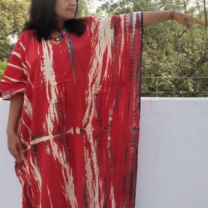 Puede incluir: Una kaft&aacute;n de color rojo y blanco con estampado tie-dye, de corte holgado y fluido. La kaft&aacute;n tiene cuello en V y est&aacute; hecha de una tela suave y c&oacute;moda.