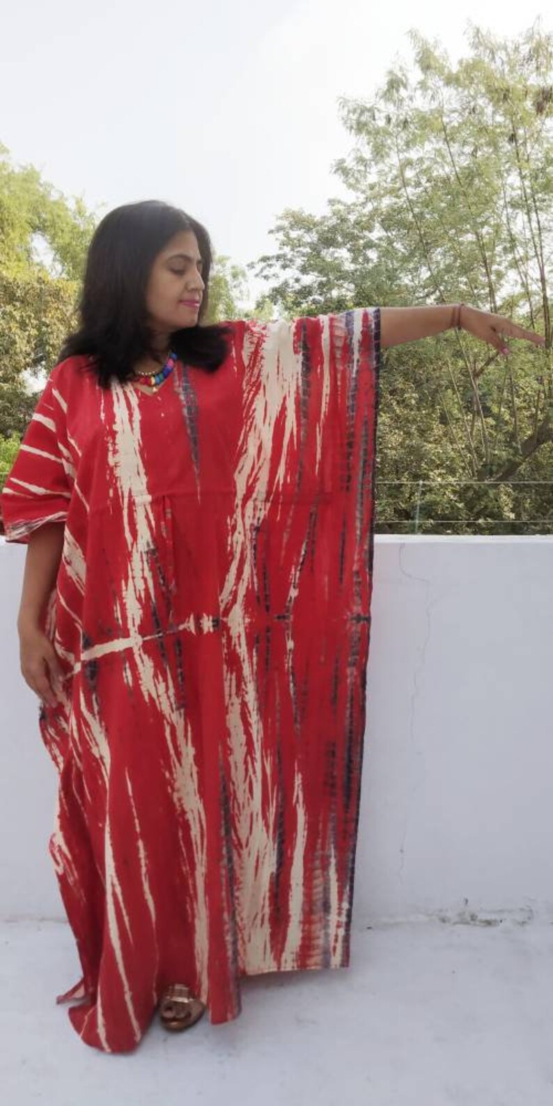 Puede incluir: Una kaft&aacute;n de color rojo y blanco con estampado tie-dye, de corte holgado y fluido. La kaft&aacute;n tiene cuello en V y est&aacute; hecha de una tela suave y c&oacute;moda.