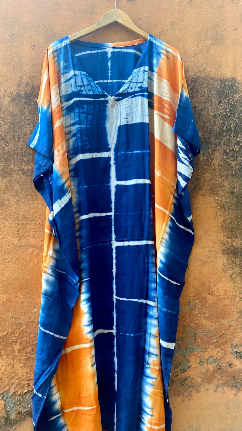 May include: A long, blue and orange tie-dye kaftan with a V-neckline. The kaftan has a loose, flowing fit and is perfect for a casual, summery look.