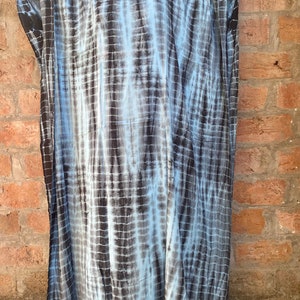 May include: A long, flowing blue and black tie-dye kaftan dress with a v-neckline.