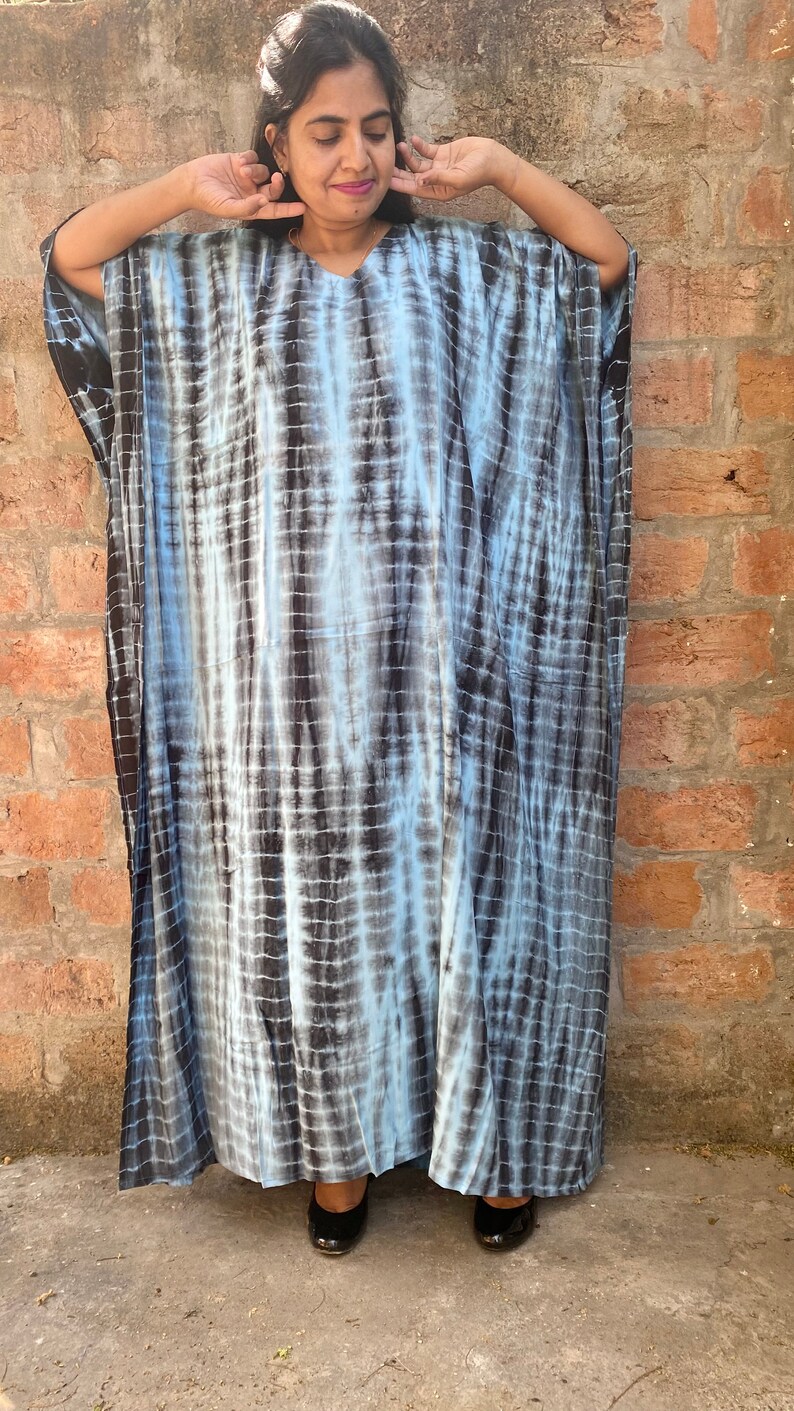May include: A long, flowing blue and black tie-dye kaftan dress with a v-neckline.