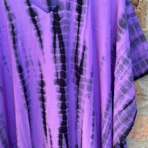 Puede incluir: Un caft&aacute;n de color morado y negro con estampado tie-dye y escote en V. El caft&aacute;n est&aacute; hecho de una tela suave y fluida y tiene un corte holgado.