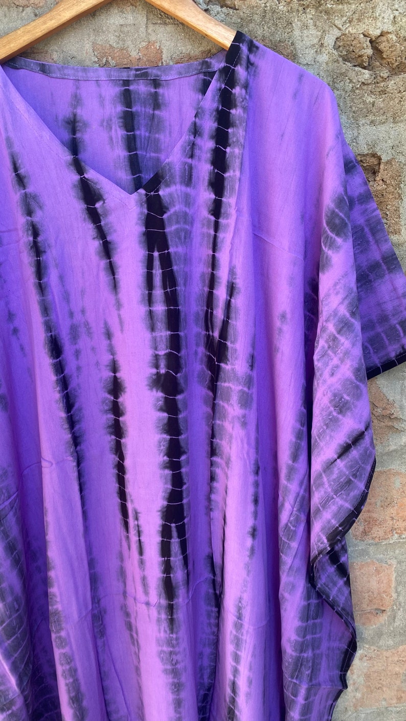 Puede incluir: Un caft&aacute;n de color morado y negro con estampado tie-dye y escote en V. El caft&aacute;n est&aacute; hecho de una tela suave y fluida y tiene un corte holgado.