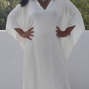 May include: A white maxi dress with long, flowing sleeves and a V-neckline. The dress is made of a lightweight fabric and has a relaxed fit.
