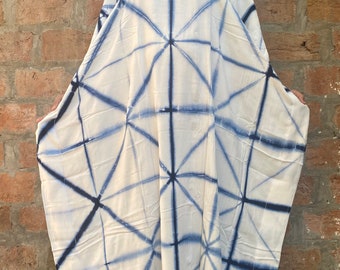 Op de afbeelding: Een witte kaftan jurk met een geometrisch blauw patroon. De jurk heeft een V-hals en wijde mouwen. De stof lijkt licht en vloeiend, geschikt voor warm weer. De jurk wordt door een persoon gedragen.