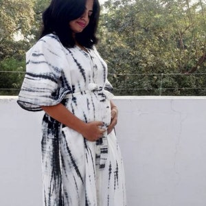 Puede incluir: Un vestido maxi blanco con un estampado tie-dye negro. El vestido tiene manga larga y un corte holgado.