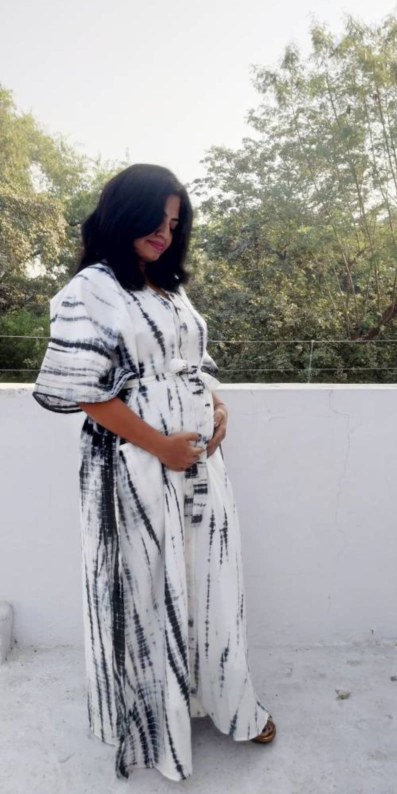 Puede incluir: Un vestido maxi blanco con un estampado tie-dye negro. El vestido tiene manga larga y un corte holgado.