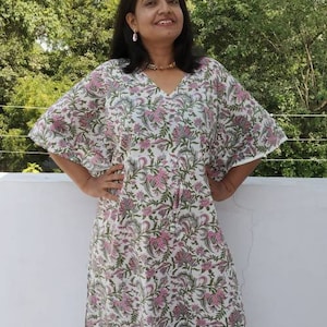 May include: A white maxi dress with a pink and green floral print. The dress has a V-neck and a flowing silhouette.
