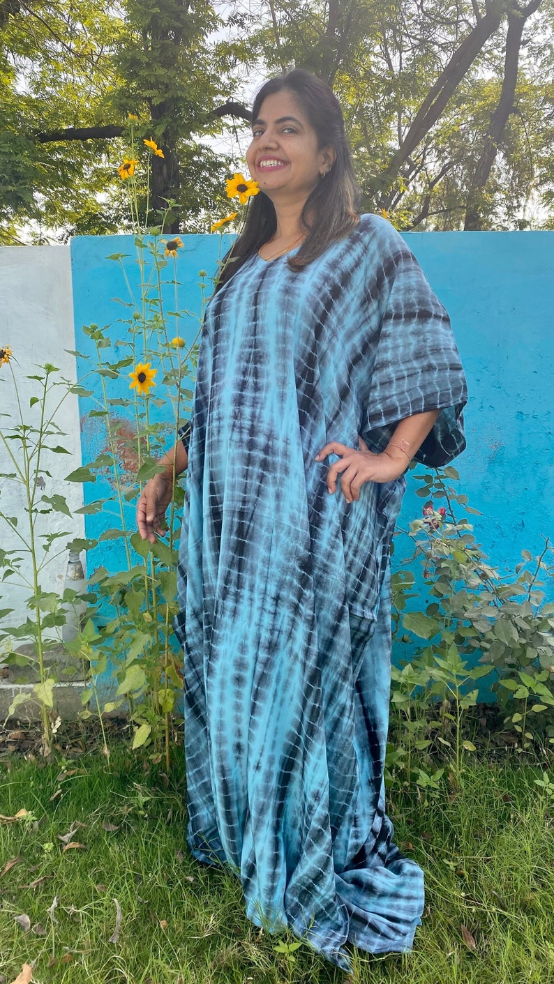 May include: A blue and black tie-dye kaftan dress with a loose fit and a V-neck.