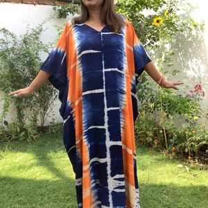 May include: A long, flowing kaftan dress with a tie-dye pattern in shades of orange, blue, and white. The dress has a V-neck and short sleeves.