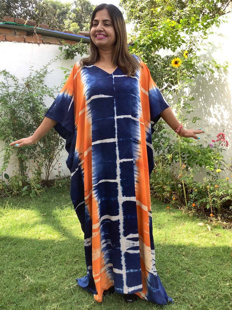 May include: A long, flowing kaftan dress with a tie-dye pattern in shades of orange, blue, and white. The dress has a V-neck and short sleeves.