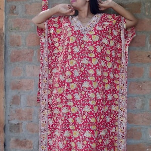 May include: A red and white floral print kaftan with a white trim. The kaftan has a V-neck and short sleeves.