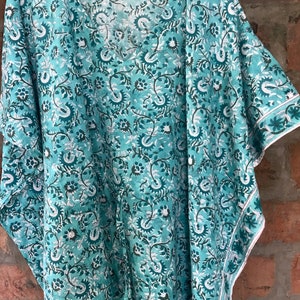May include: A teal blue cotton kimono with a floral print. The kimono has a V-neck and short sleeves.