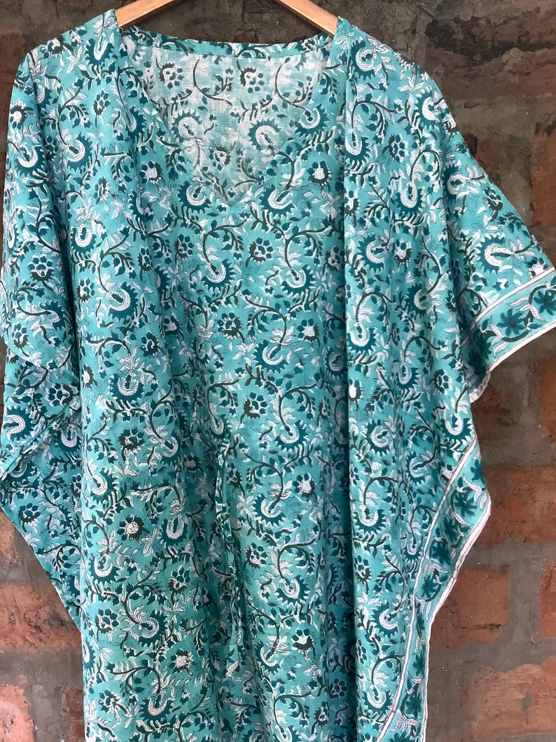 May include: A teal blue cotton kimono with a floral print. The kimono has a V-neck and short sleeves.