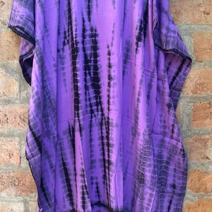 Puede incluir: Kaft&aacute;n de color morado y negro con estampado tie-dye, de corte holgado y cuello en V.