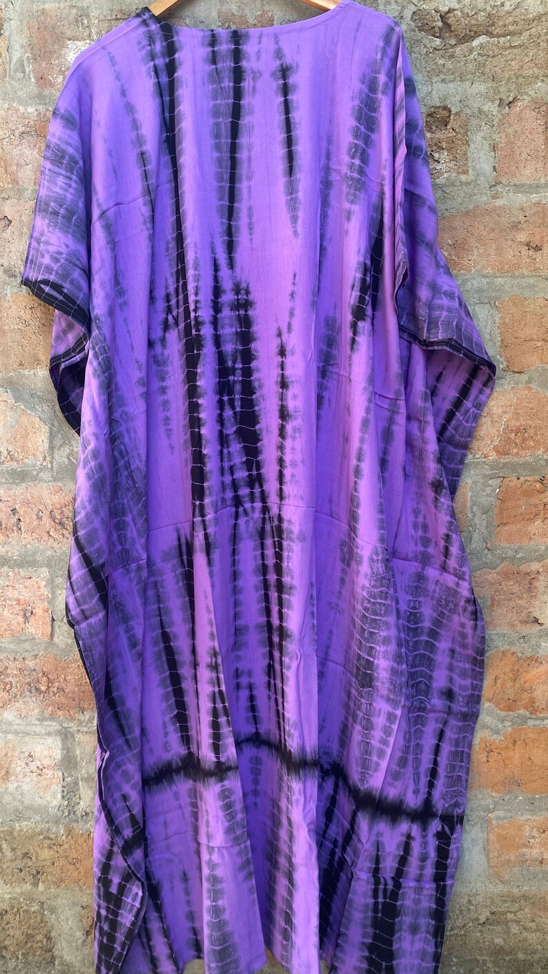 Puede incluir: Kaft&aacute;n de color morado y negro con estampado tie-dye, de corte holgado y cuello en V.